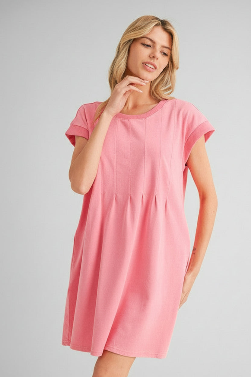Woman wearing pink solid knit knee length dress with dart detailing on beige background