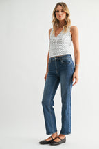 Woman wearing a white patterned top and blue jeans on a white background