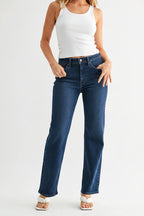 Woman wearing dark denim mid-rise straight leg jeans and a strapless top on a white background