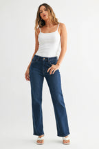Woman wearing dark denim mid-rise straight leg jeans and a strapless top on a white background
