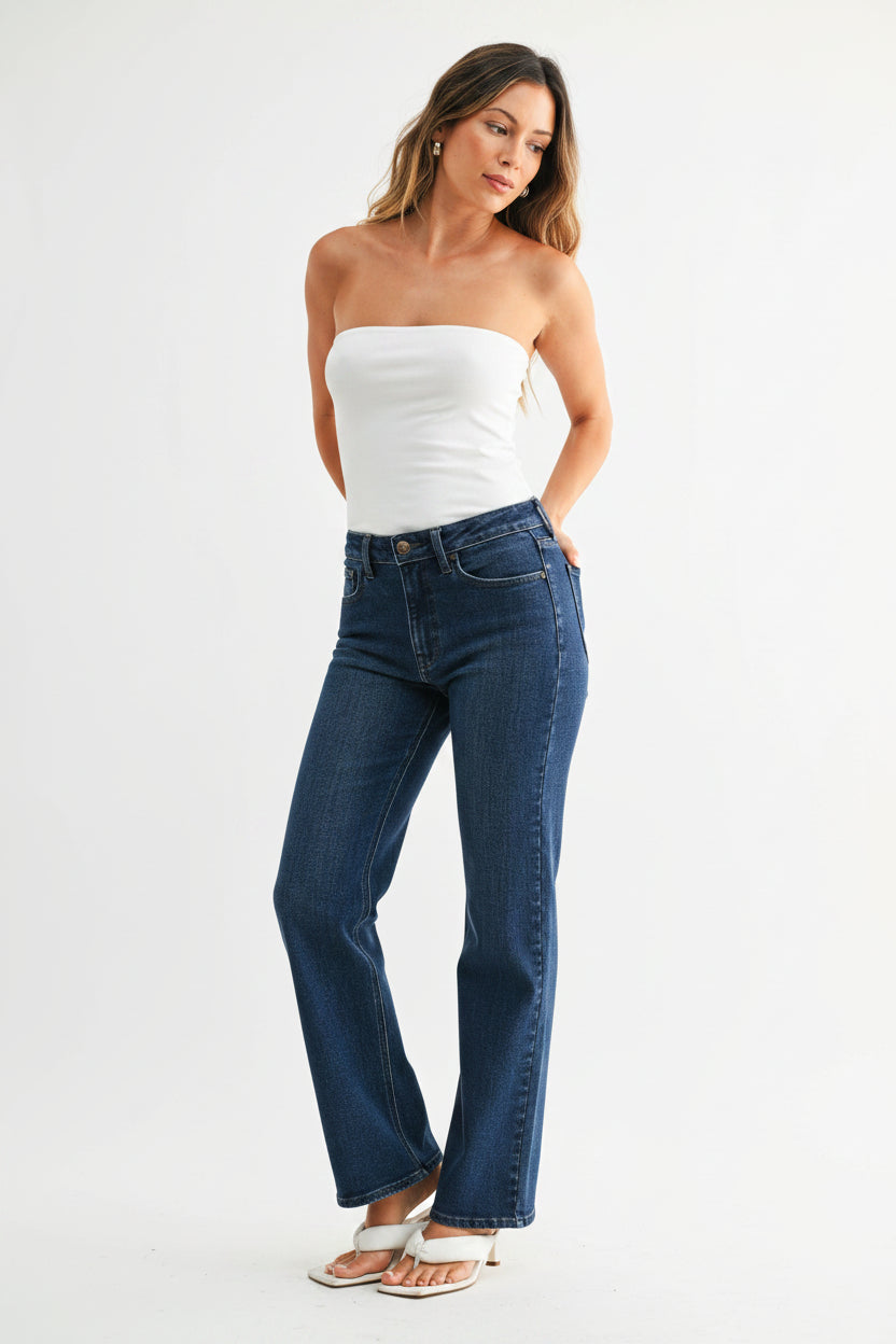 Woman wearing dark denim mid-rise straight leg jeans and a strapless top on a white background
