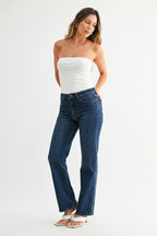 Woman wearing dark denim mid-rise straight leg jeans and a strapless top on a white background