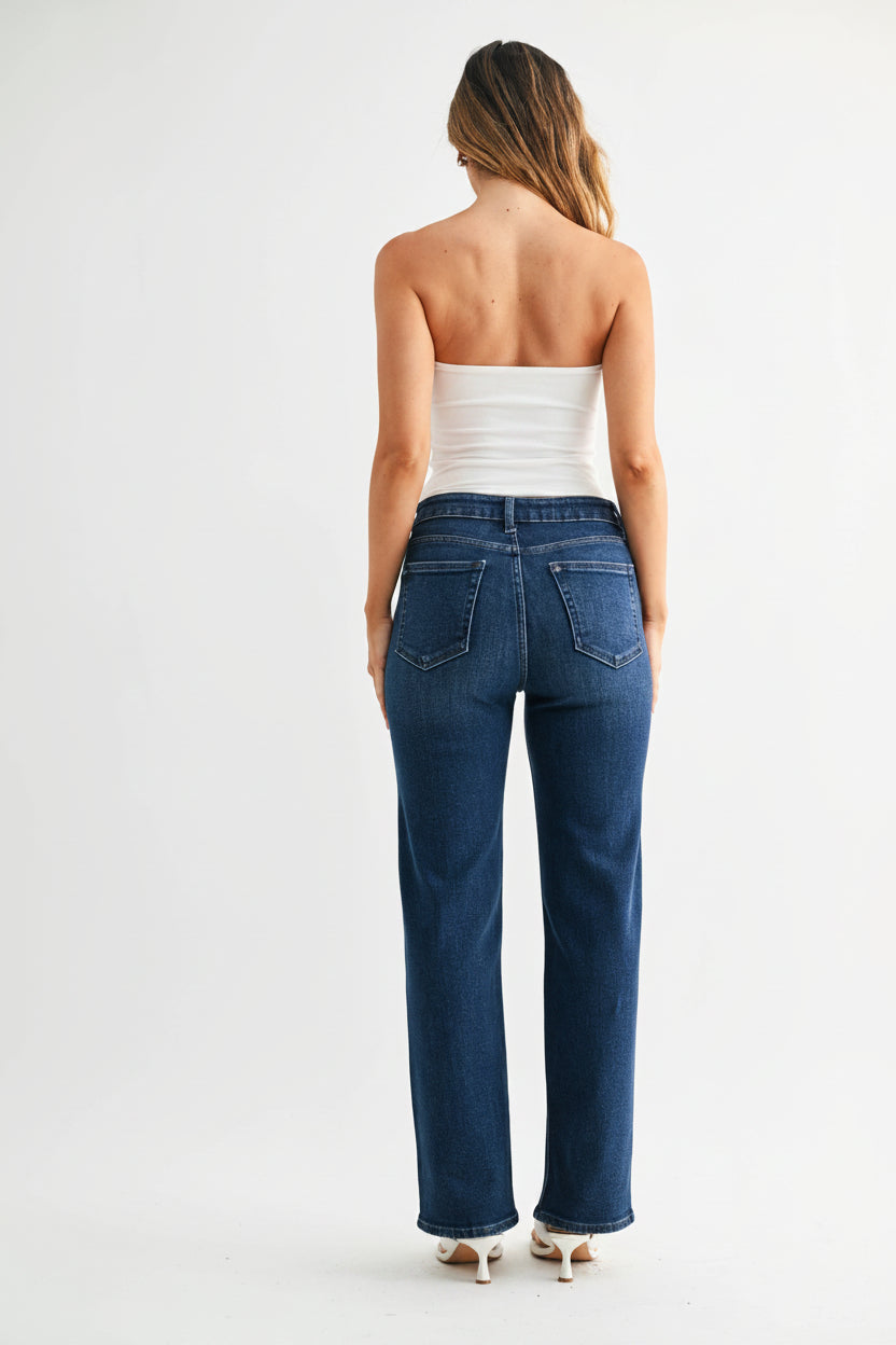 Back view of a woman wearing dark denim mid-rise straight leg jeans and a strapless top on a white background