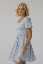 Woman wearing a light blue floral dress against a plain background