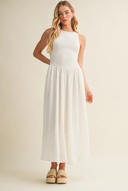 Woman wearing an off white bubble texture maxi dress on a plain background