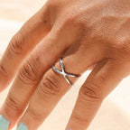 Woman wearing a criss cross silver ring with a light background