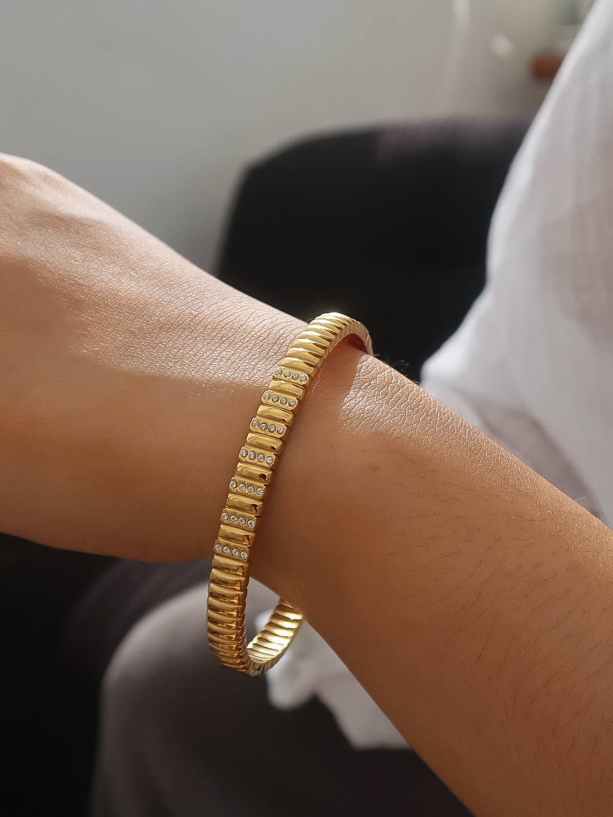 Gold bracelet on a wrist with a blurred background