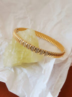 Gold bracelet with small stones on a white fabric background