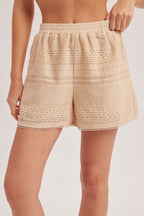 Woman wearing natural crochet and lace trim short against a white background