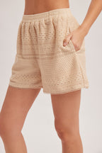 Woman wearing natural crochet and lace trim short against a white background