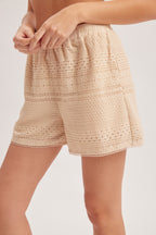 Woman wearing natural crochet and lace trim short against a white background