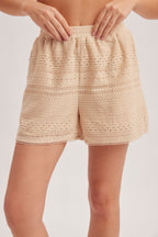 Woman wearing natural crochet and lace trim short against a white background