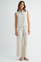 Woman wearing natural wide-leg pants with frayed detail on a plain background