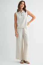Woman wearing natural wide-leg pants with frayed detail on a plain background