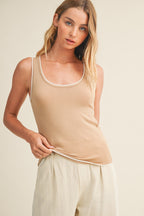 Woman wearing a latte knit tank top and pants against a beige background
