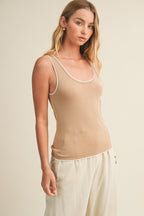 Woman wearing a latte knit tank top and pants against a beige background