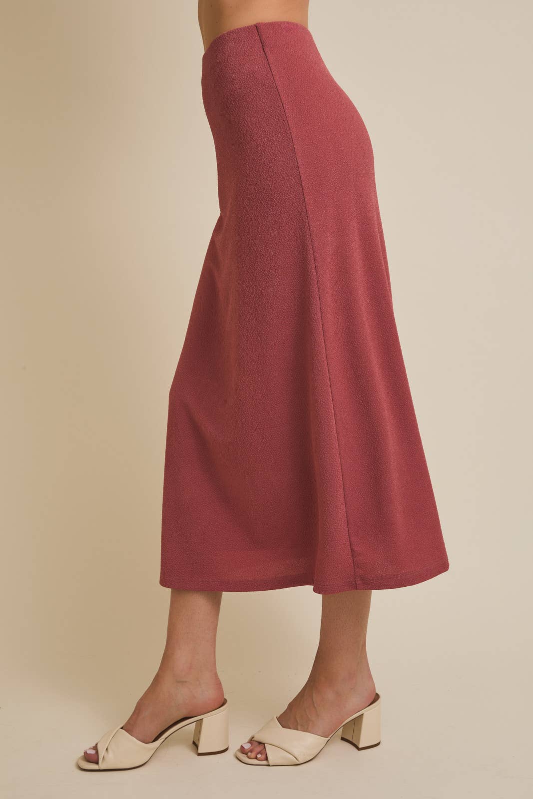 Woman wearing a mauve skirt on a beige background