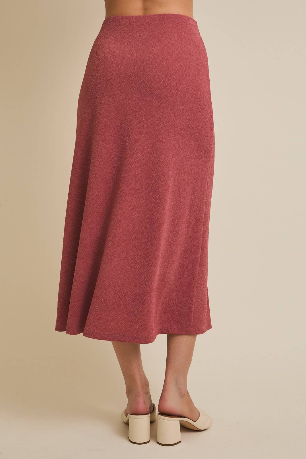 Woman wearing a mauve skirt on a beige background