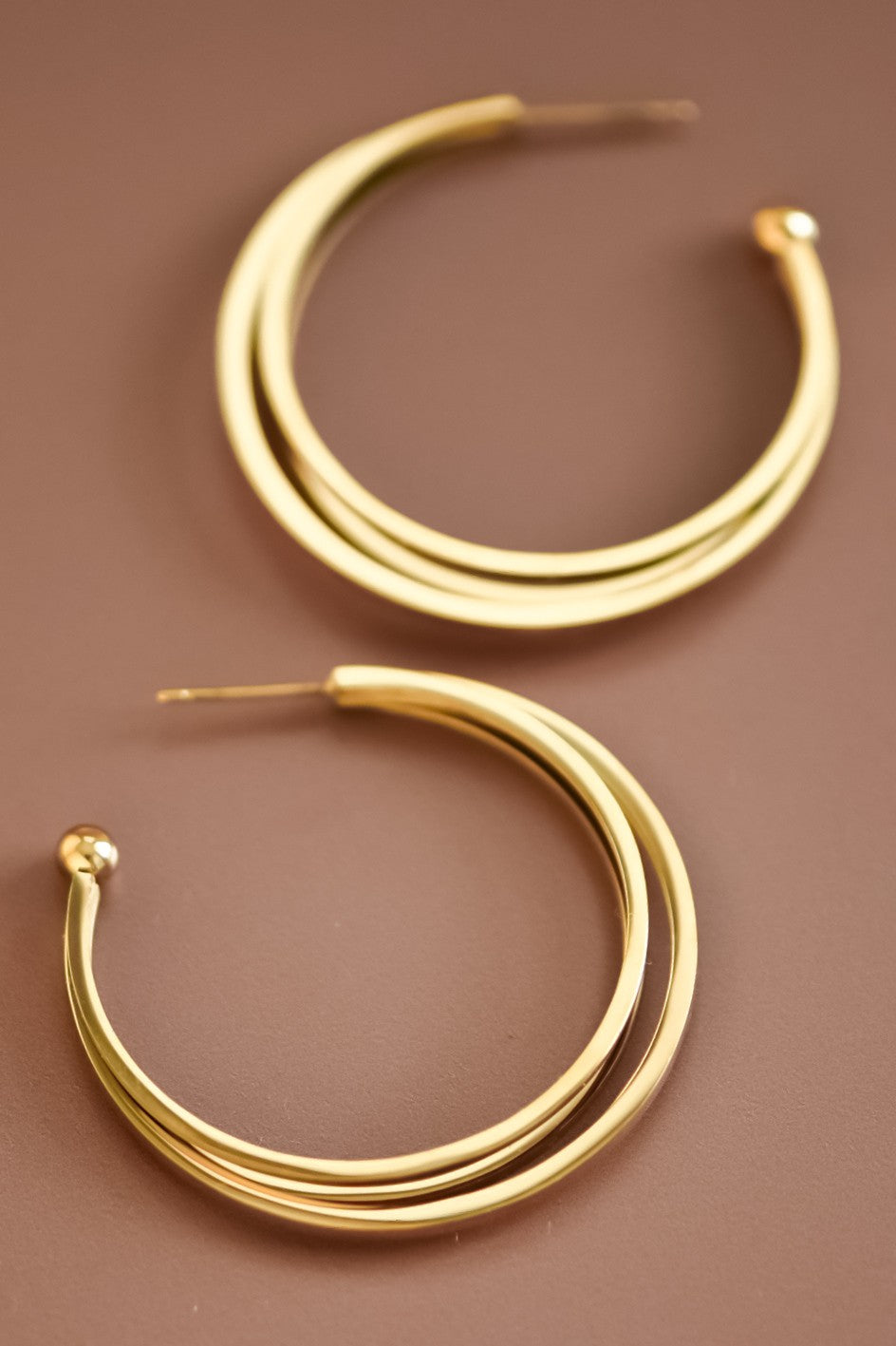 18k gold-plated stainless steel triple hoop earrings on a brown background
