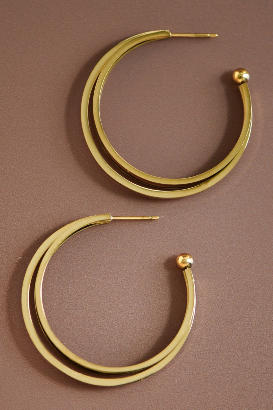 18k gold-plated stainless steel triple hoop earrings on a brown background