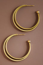 18k gold-plated stainless steel triple hoop earrings on a brown background