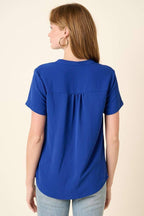 Back view of a woman wearing a royal blue top on a beige background