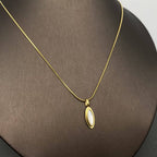 18k gold-plated necklace with a inlaid shell pendant on a brown surface