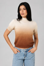 Woman wearing an ombre mock neck short sleeve sweater against a white drape background