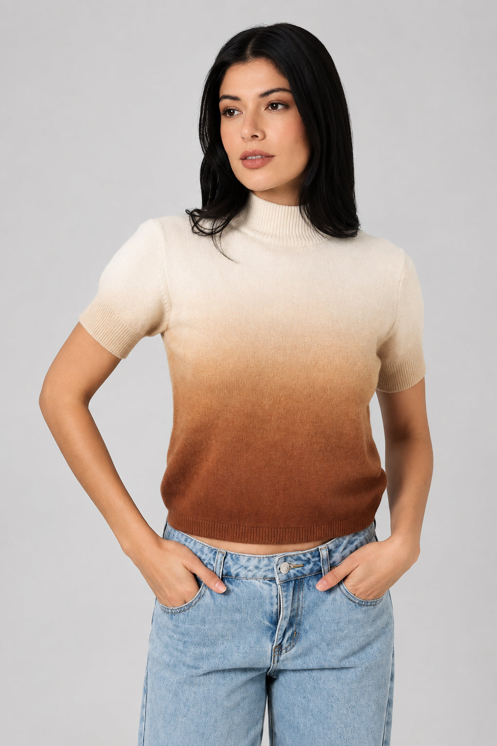Woman wearing an ombre mock neck short sleeve sweater against a white drape background