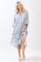 Woman wearing a striped blue oversized shirt dress on a white background