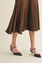 Woman wearing an espresso flare midi skirt on a beige background