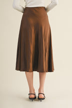 Back view of a woman wearing an espresso flare midi skirt on a beige background