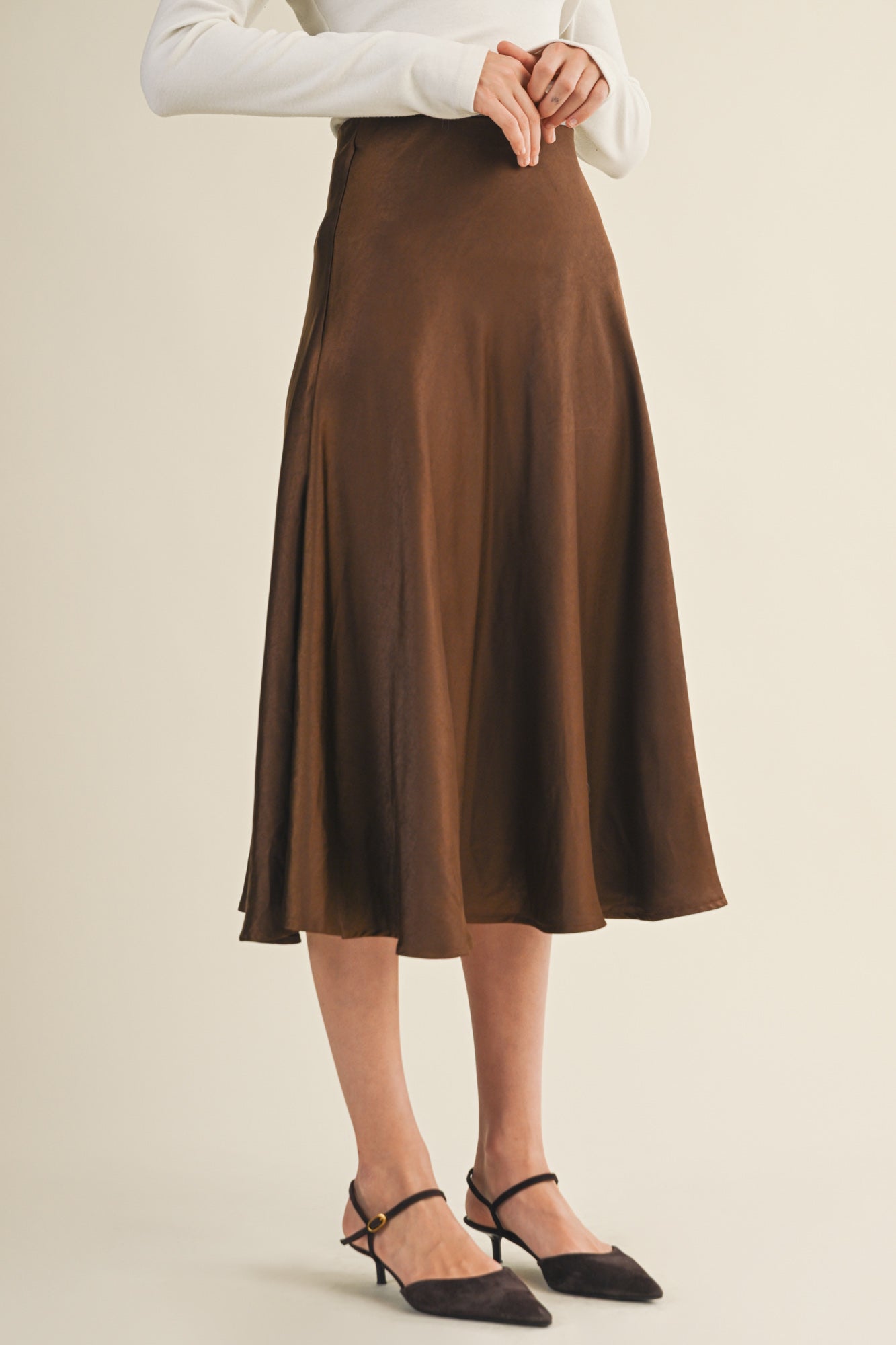 Woman wearing an espresso flare midi skirt on a beige background