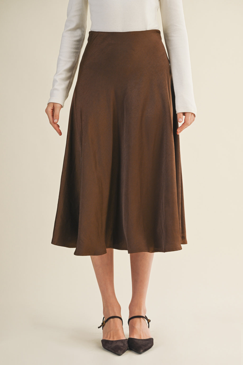 Woman wearing an espresso flare midi skirt on a beige background