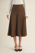 Woman wearing an espresso flare midi skirt on a beige background
