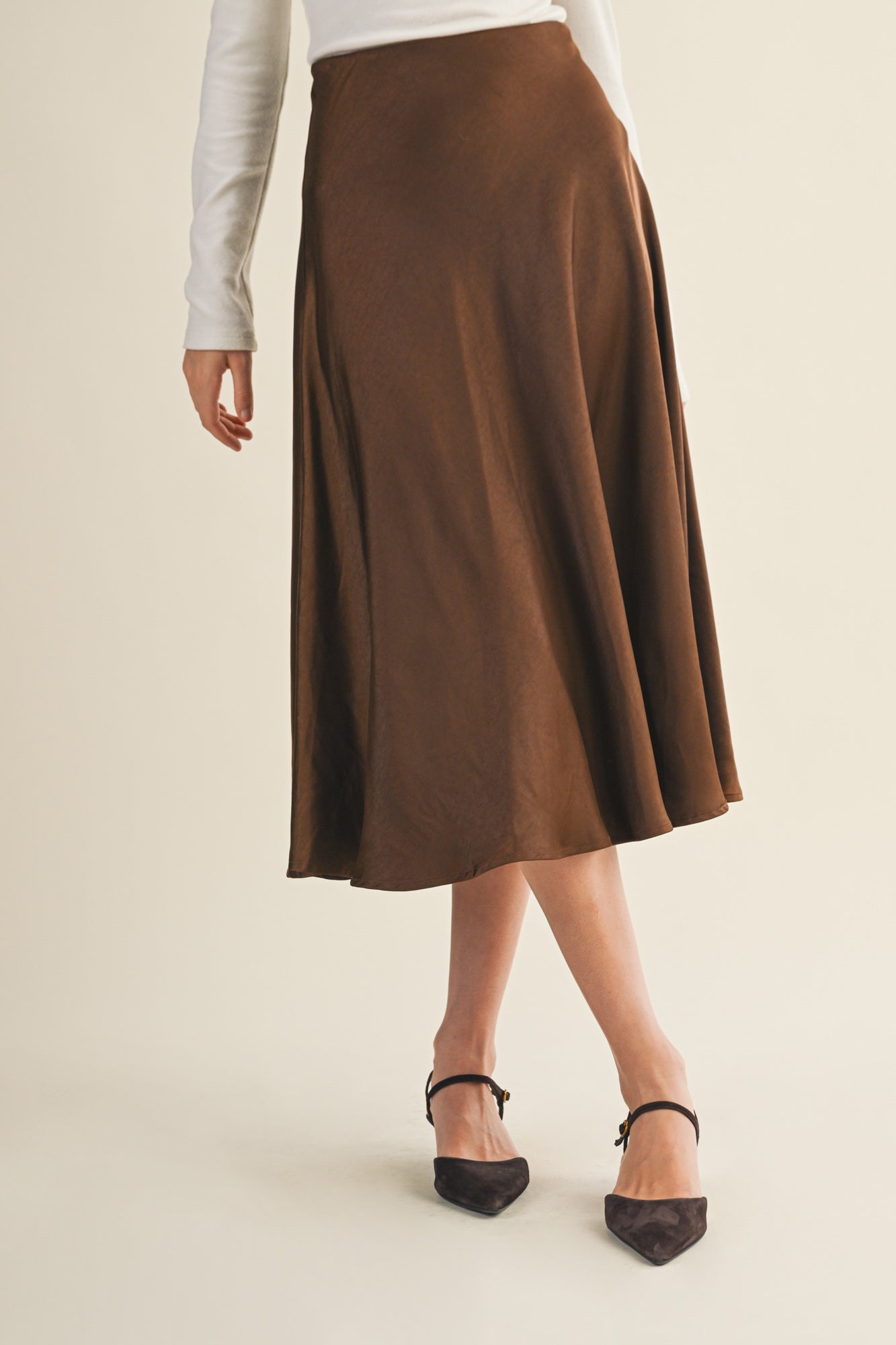 Woman wearing an espresso flare midi skirt on a beige background