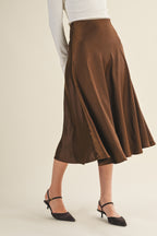 Woman wearing an espresso flare midi skirt on a beige background