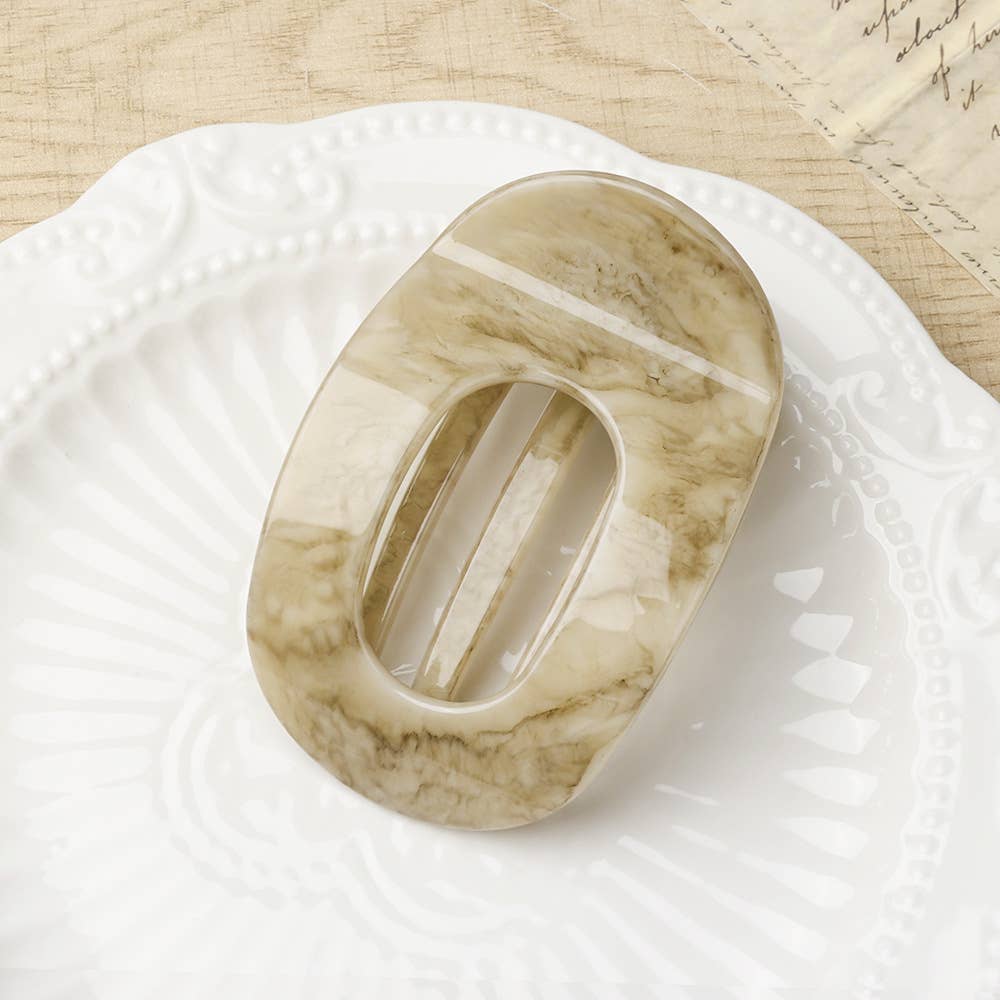Beige marble-patterned oval flat hair claw on a white surface