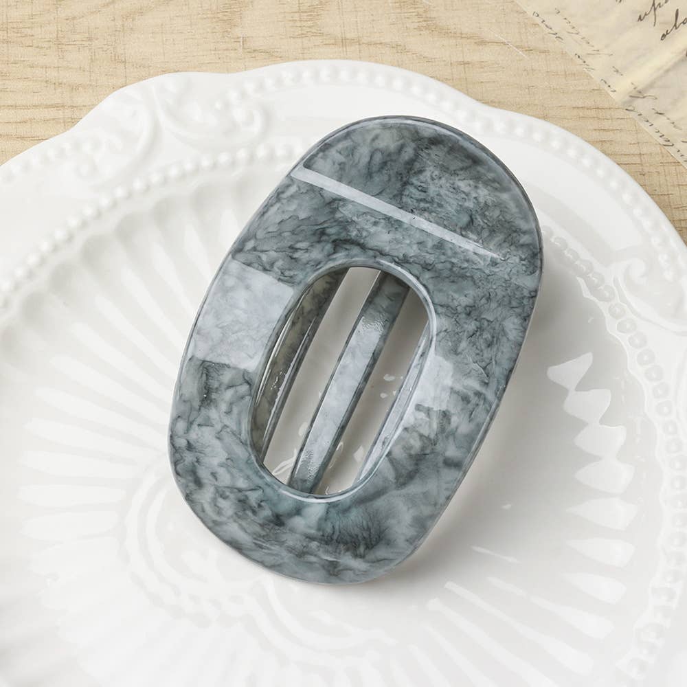 Gray marble-patterned oval flat hair claw on a white surface