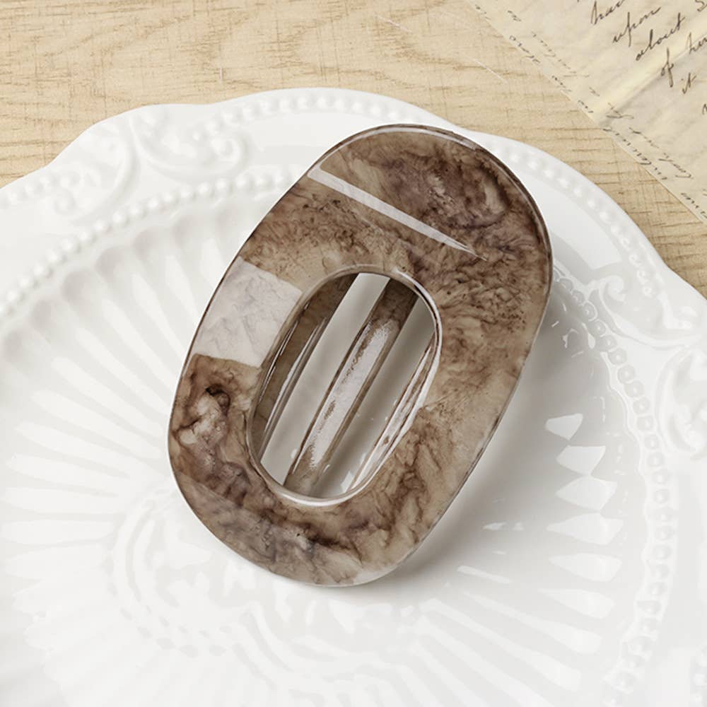 Brown marble-patterned oval flat hair claw on a white surface