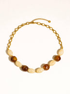 Brown and ivory beads with delicate gold tone beads and link chain on white background