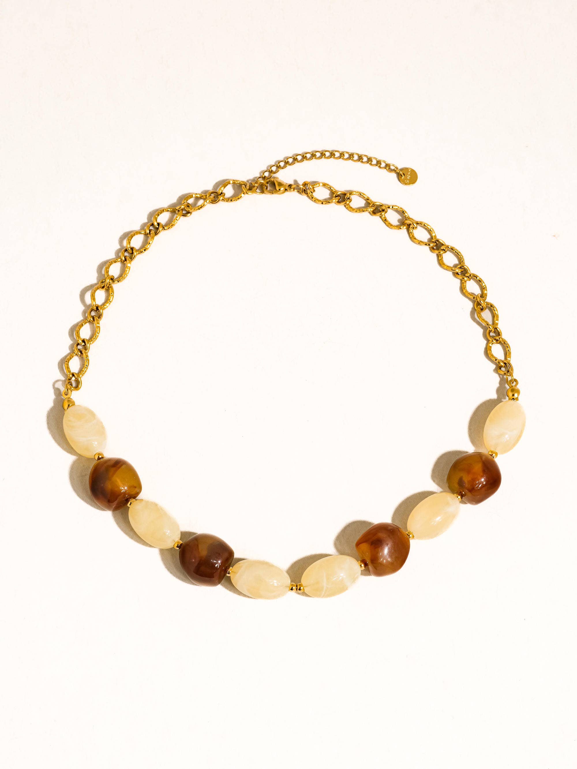 Brown and ivory beads with delicate gold tone beads and link chain on white background