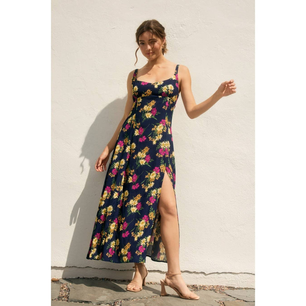 Woman wearing a navy floral dress with side slit against a light background