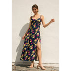 Woman wearing a navy floral dress with side slit against a light background