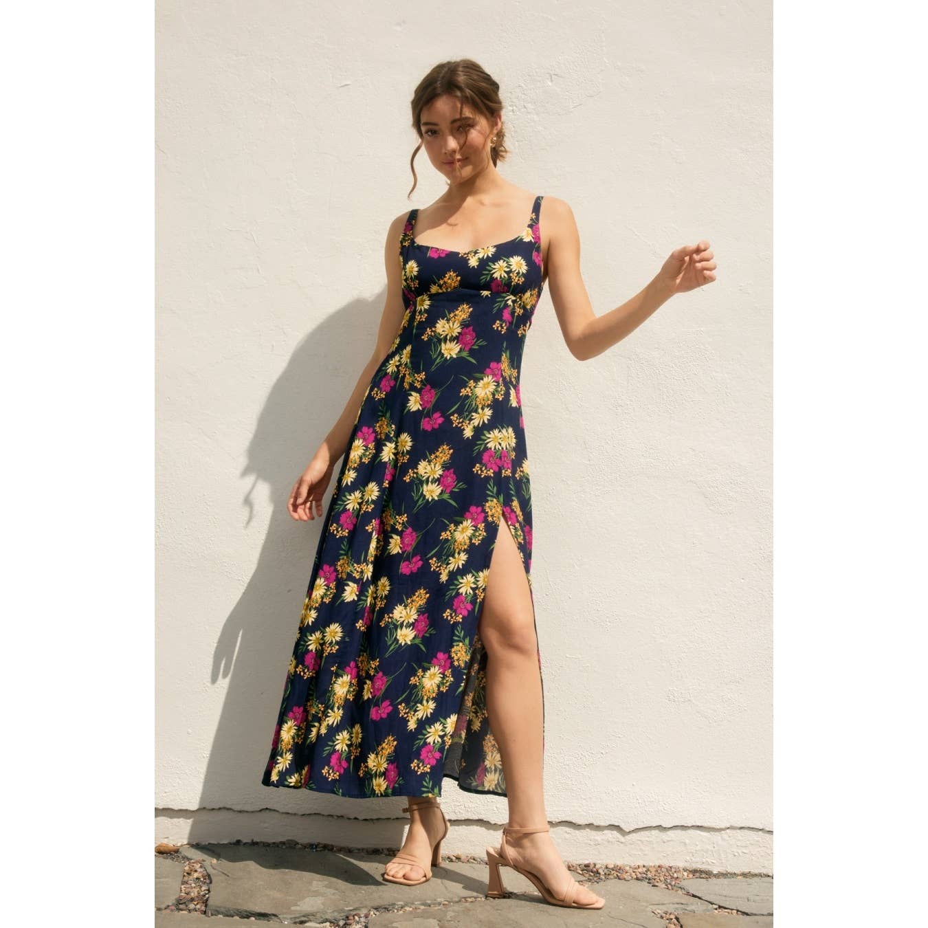 Woman wearing a navy floral dress with side slit against a light background