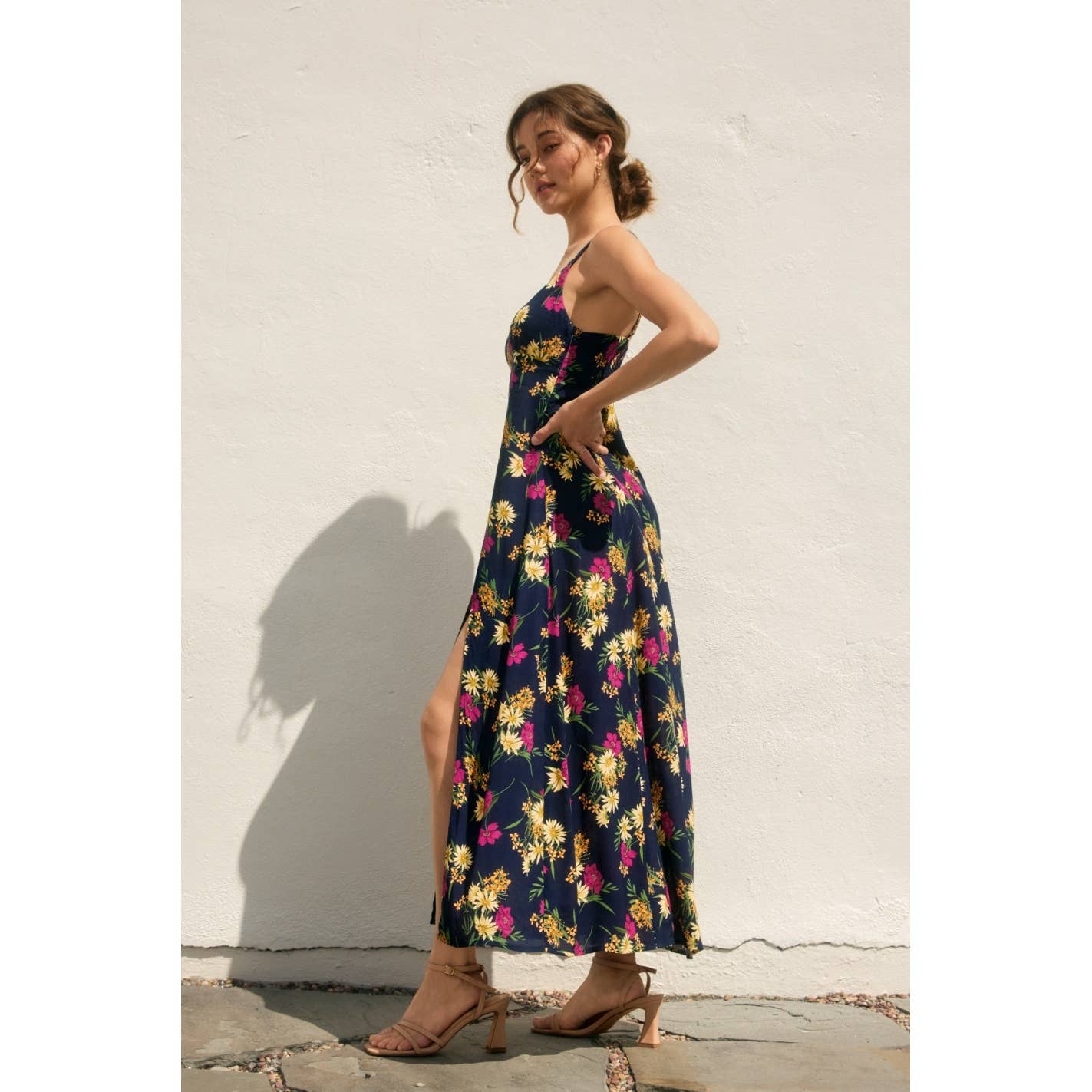 Woman wearing a navy floral dress with side slit against a light background