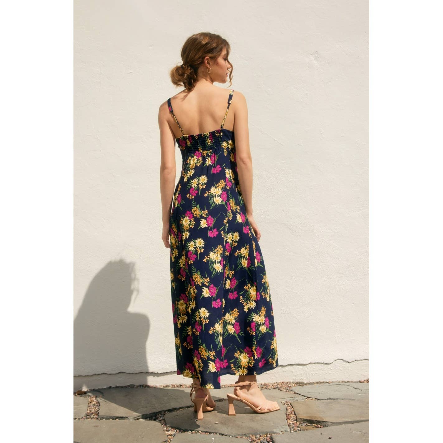 Back view of a woman wearing a navy floral dress with side slit against a light background