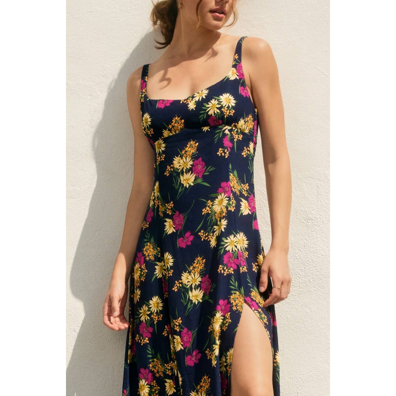Woman wearing a navy floral dress with side slit against a light background