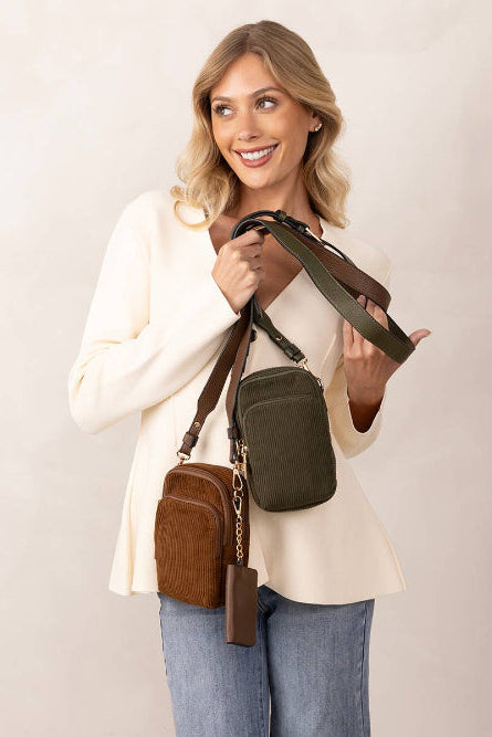 Woman holding corduroy three compartment crossbody bags with detachable strap and separate snap coin bag on a white background