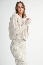 Woman wearing a light taupe sweater and white lace skirt on a white background